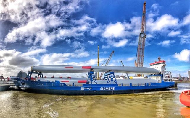 Immense wieken van windmolens varen Oostendse haven in